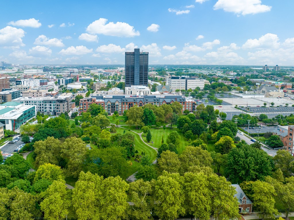 a cityscape with a tall building in the background and trees in the foreground