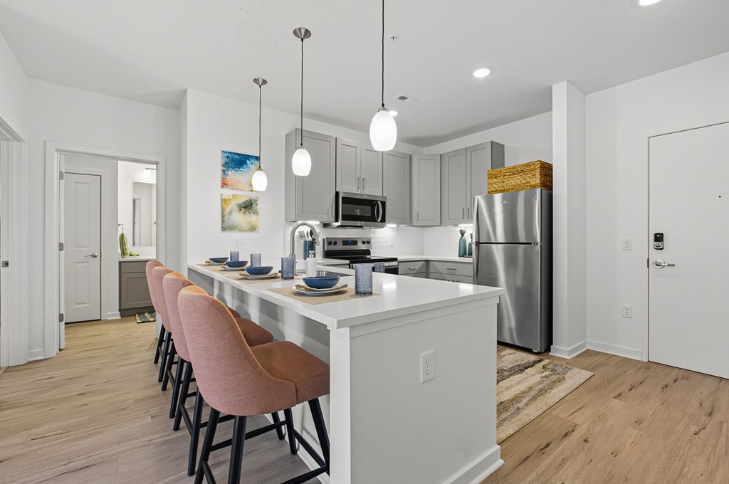A kitchen with a white island and pink chairs.