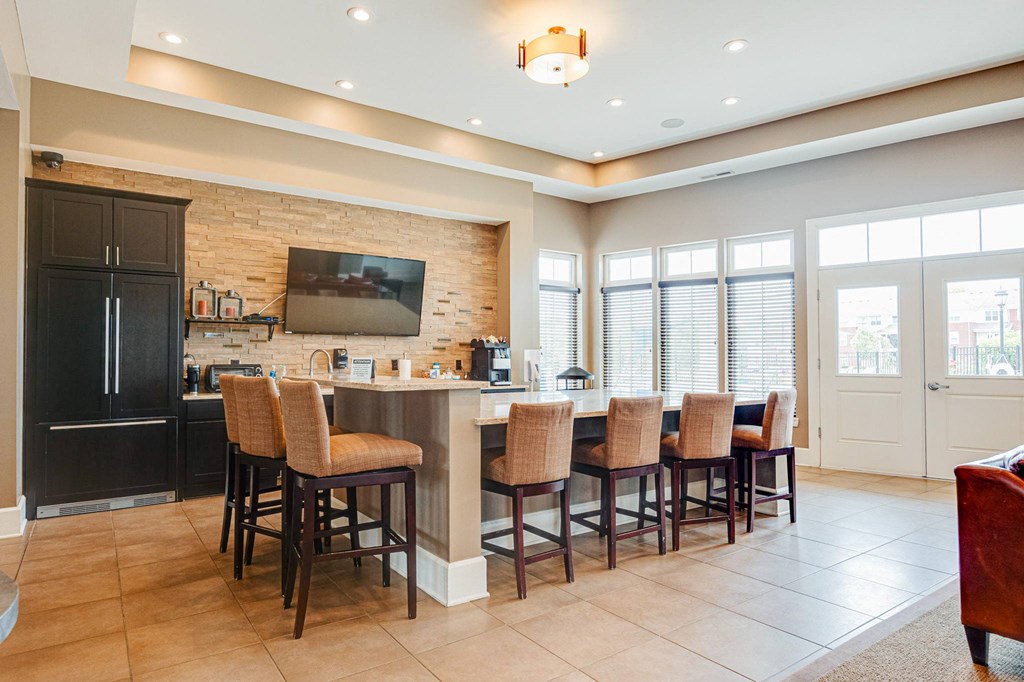 a kitchen with a bar with chairs and a television