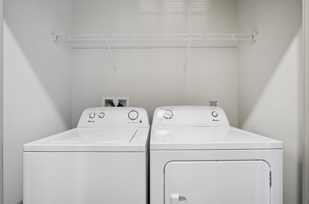 Two white washing machines in a small laundry room.