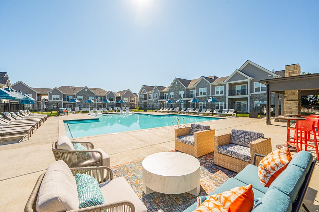 A sunny day at a poolside with lounge chairs and umbrellas.