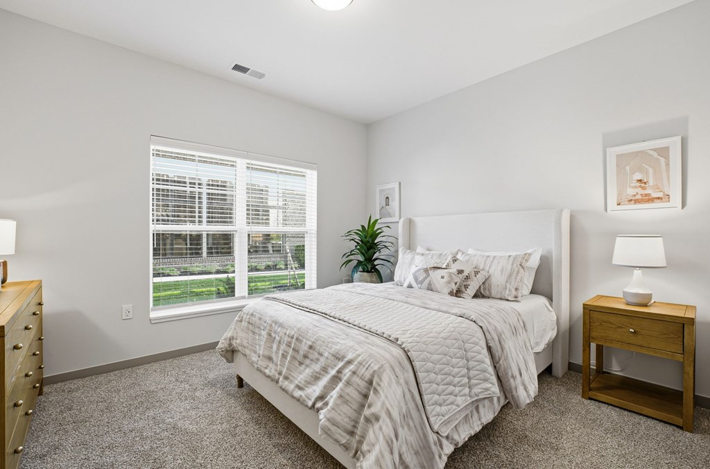 A bedroom with a bed, nightstand, and window.