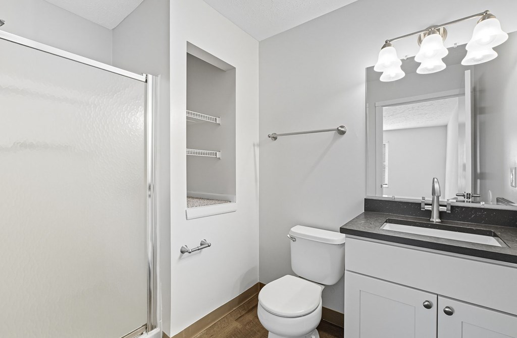 A white bathroom with a toilet, sink, and mirror.