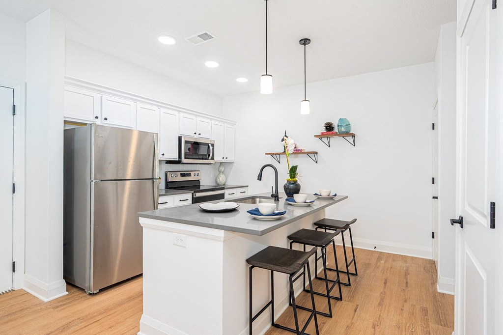 A kitchen with white cabinets and a stainless steel refrigerator.