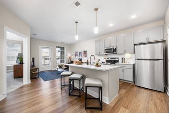 A modern kitchen with a bar stool and a refrigerator.