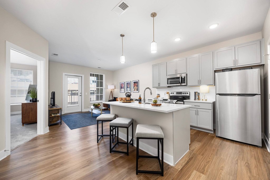 A modern kitchen with a bar stool and a refrigerator.