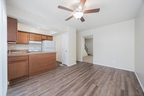 A room with a brown floor and a ceiling fan.