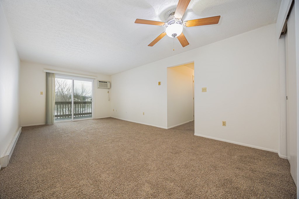 A room with a ceiling fan and carpeted floor.