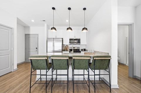 A kitchen with a table and chairs in the middle.
