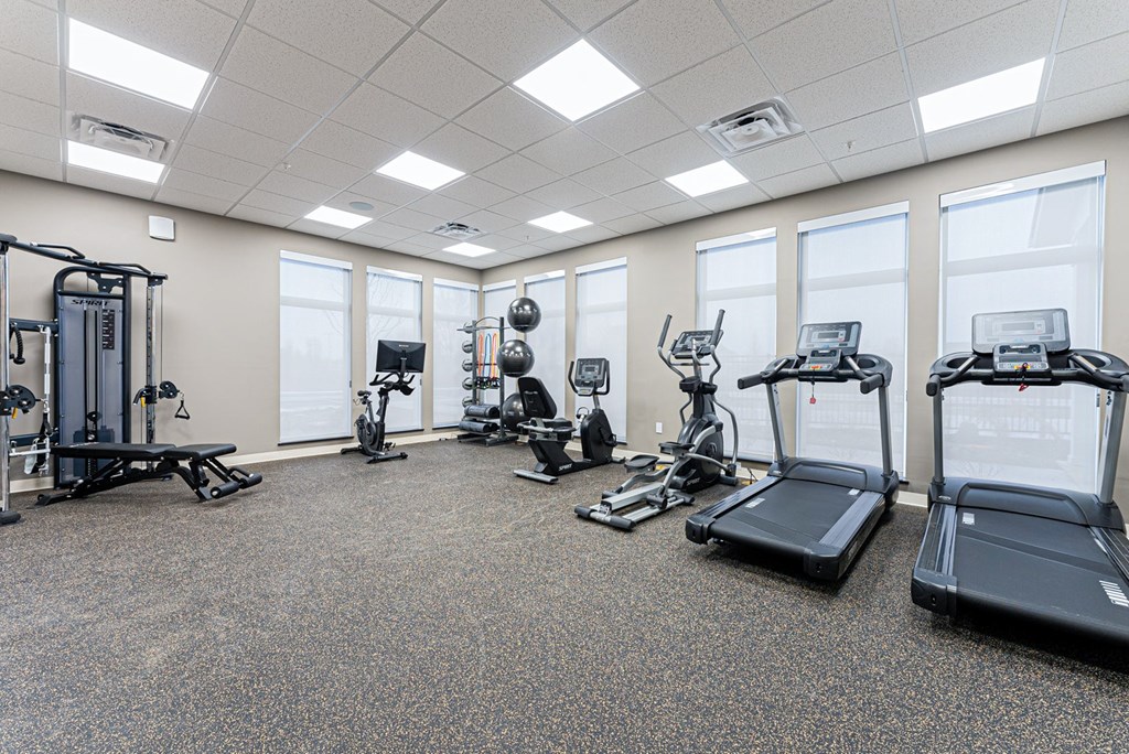 A spacious gym with a variety of equipment including treadmills, elliptical machines, and weight machines.