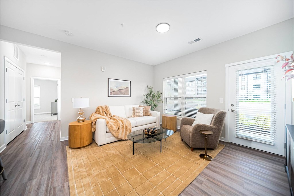 A living room with a white couch, a wooden coffee table, and a brown rug.