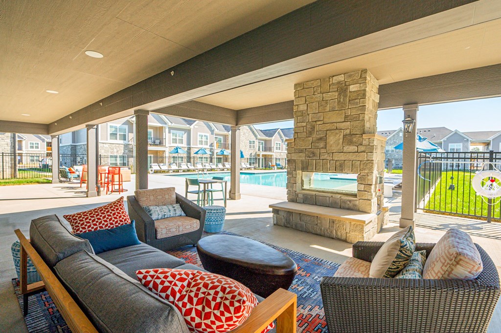 A patio with a grey couch and a stone fireplace.