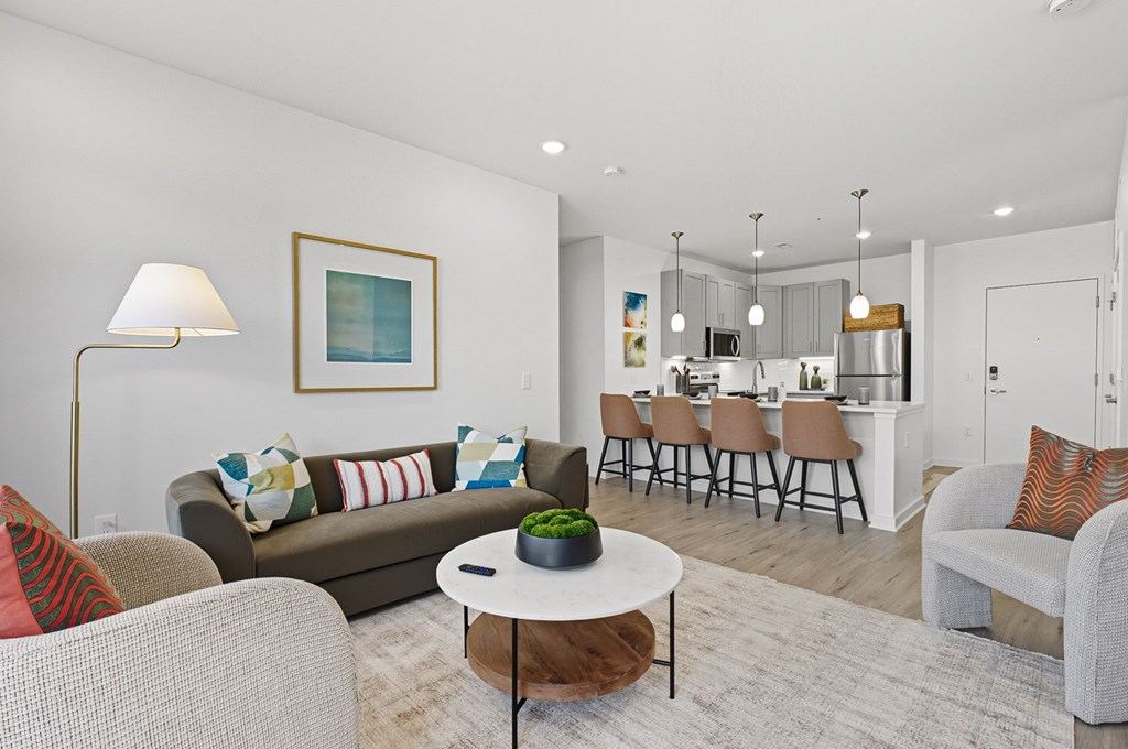 A living room with a grey couch, a white coffee table, and a painting on the wall.