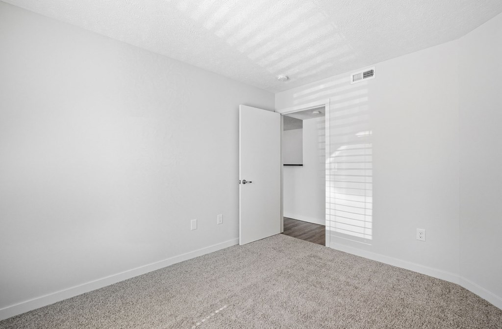 A room with a white door and a carpeted floor.