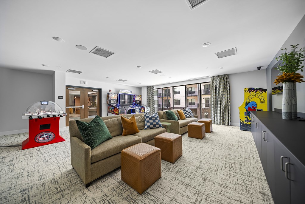 A room with a couch, a coffee table, and a gaming machine.