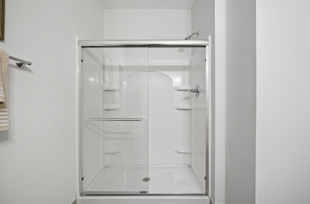 A white bathroom with a glass shower door.