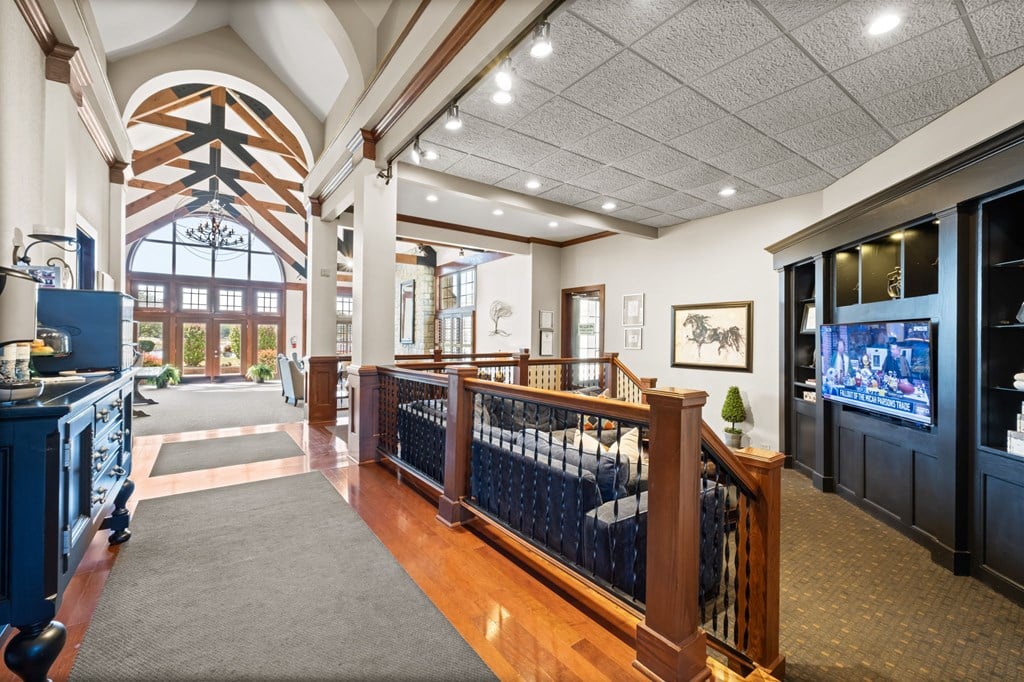 A large room with a balcony and a TV on the wall.