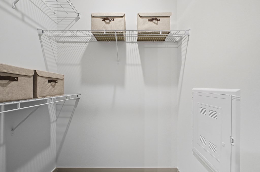 A white refrigerator is in a kitchen with two wire shelves above it.