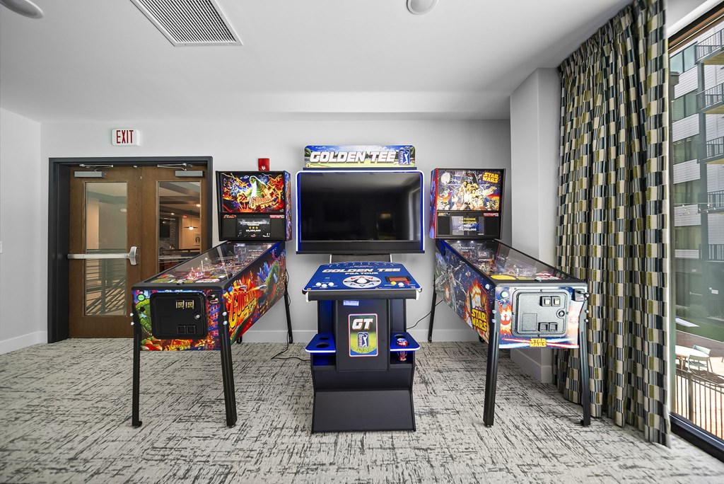 A room with two pinball machines and a table tennis table.