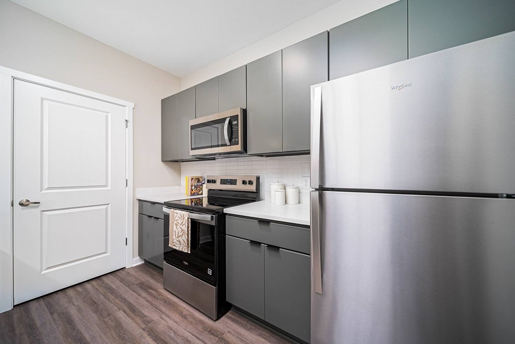 A kitchen with a stainless steel refrigerator, microwave, and oven
