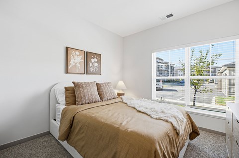 A bedroom with a large bed and two pictures on the wall.