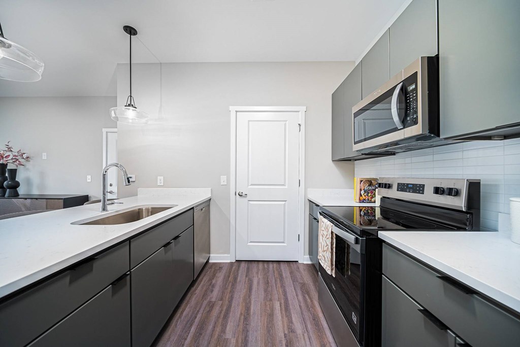 A modern kitchen with dark wood floors and white cabinetry.