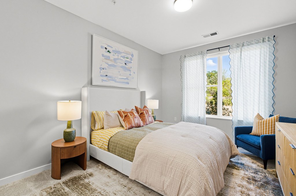 A bedroom with a large bed, a side table with a lamp, and a painting on the wall.