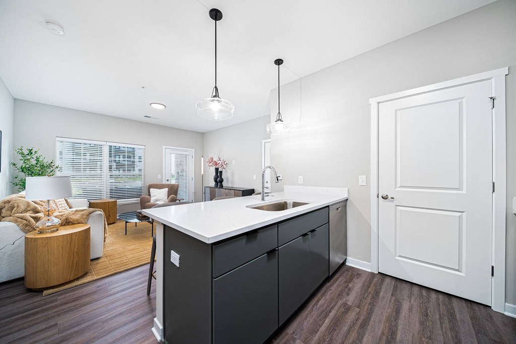 A modern kitchen with dark wood floors and white walls.