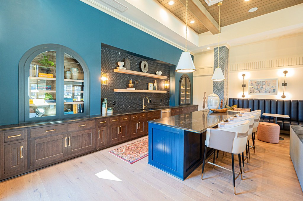A kitchen with a blue island and white chairs.
