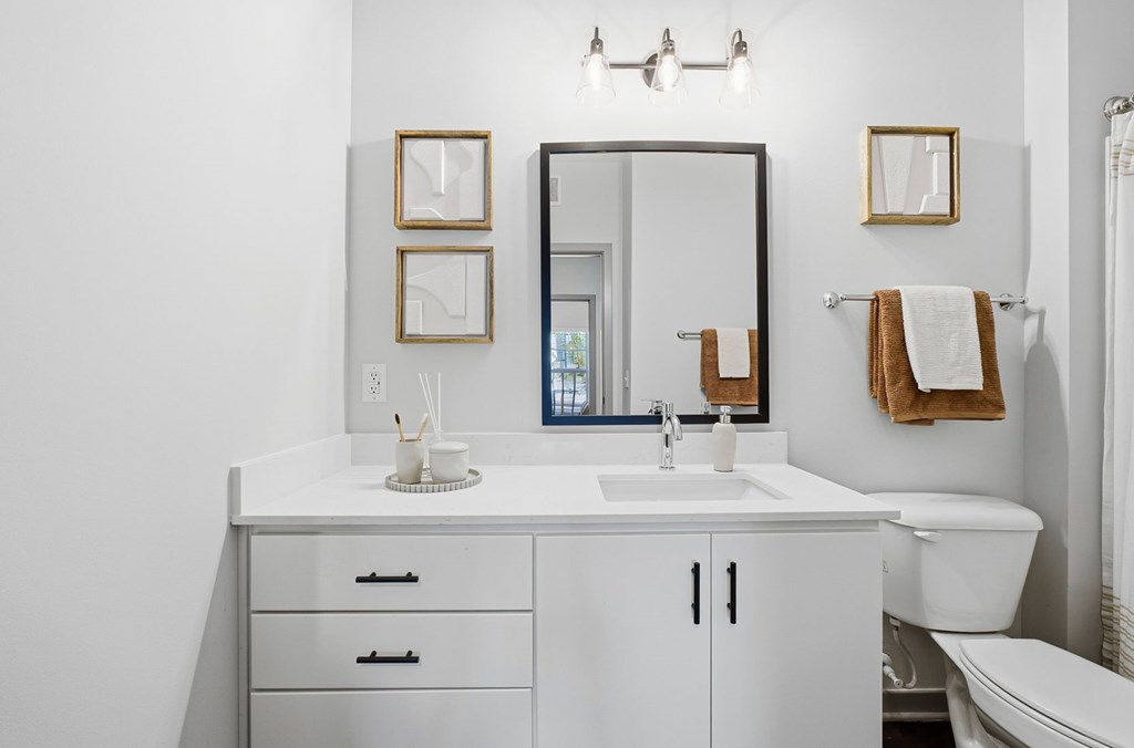 A white bathroom with a sink, mirror, and toilet.