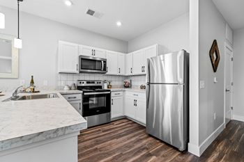 A modern kitchen with a marble countertop and stainless steel appliances.