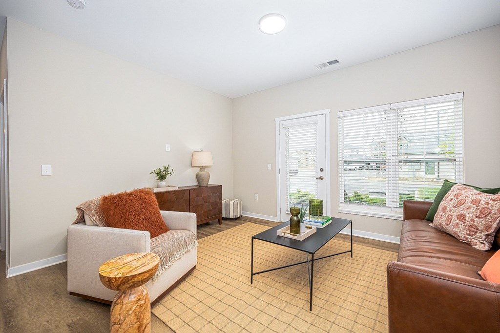 A living room with a brown leather couch, a white sofa, and a wooden coffee table.
