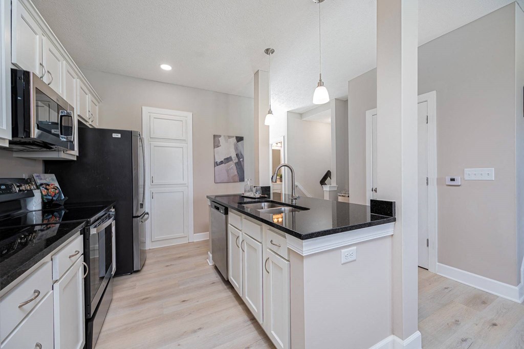 a kitchen with black counter tops and white cabinets