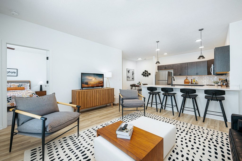 a living room with a kitchen and a bar with stools