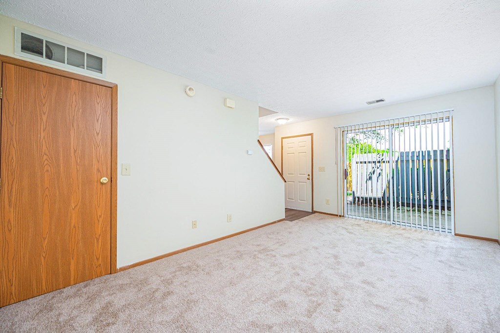 an empty living room with a door to a balcony