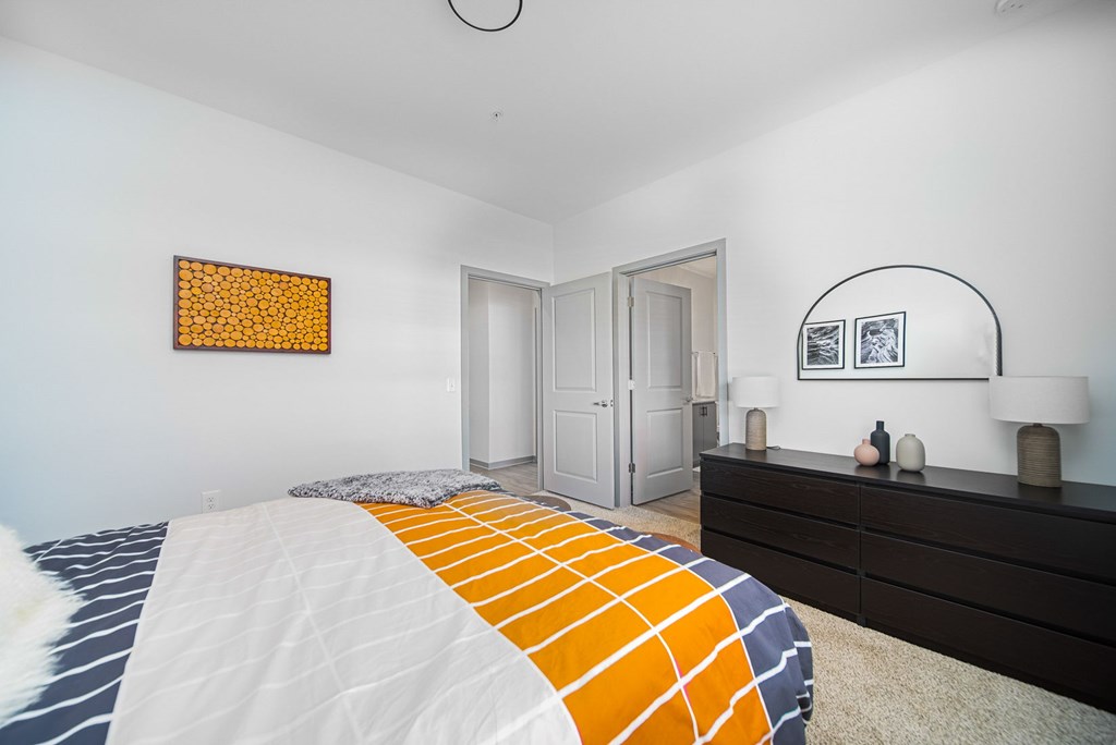 A bedroom with a bed, dresser, and two framed pictures on the wall.