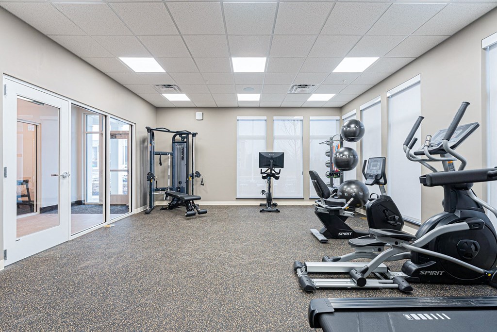 A spartan room with a treadmill, weights and exercise equipment.