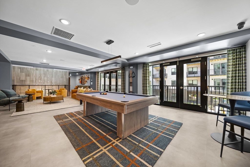 A room with a pool table and a view of the city.