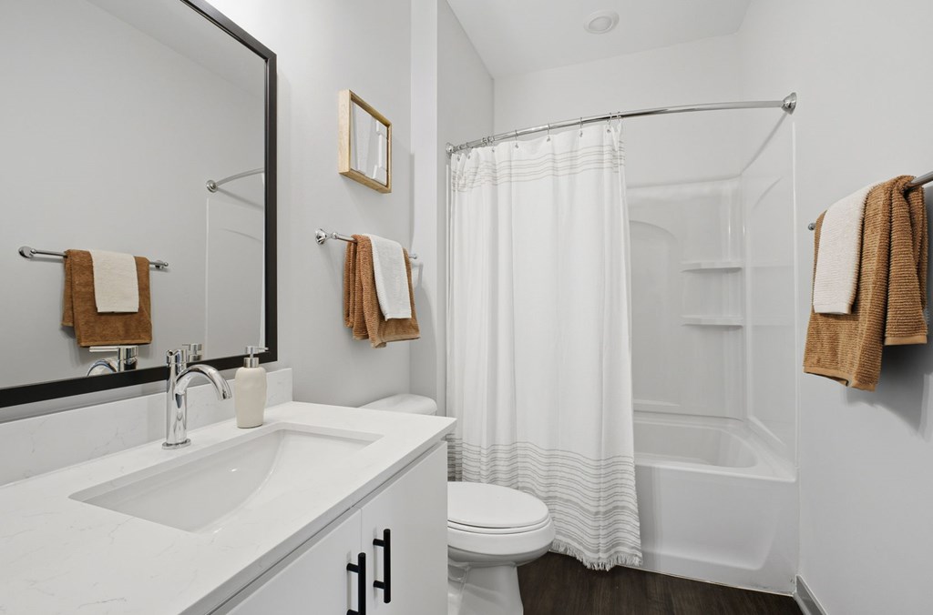 A white bathroom with a towel hanging on the wall.
