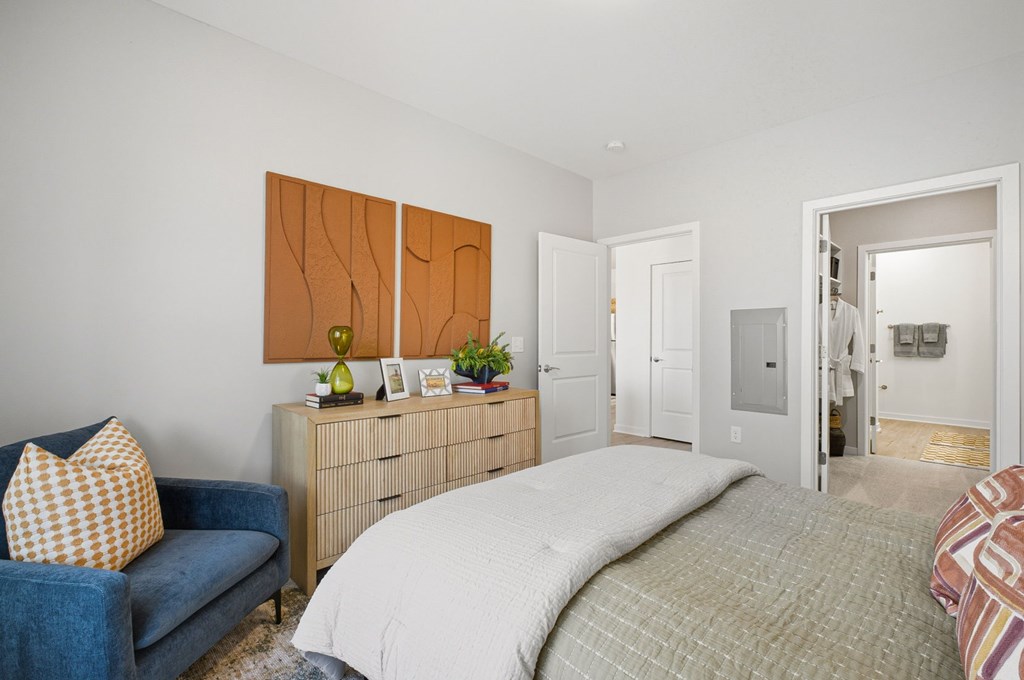 A bedroom with a bed, a couch, and a dresser.