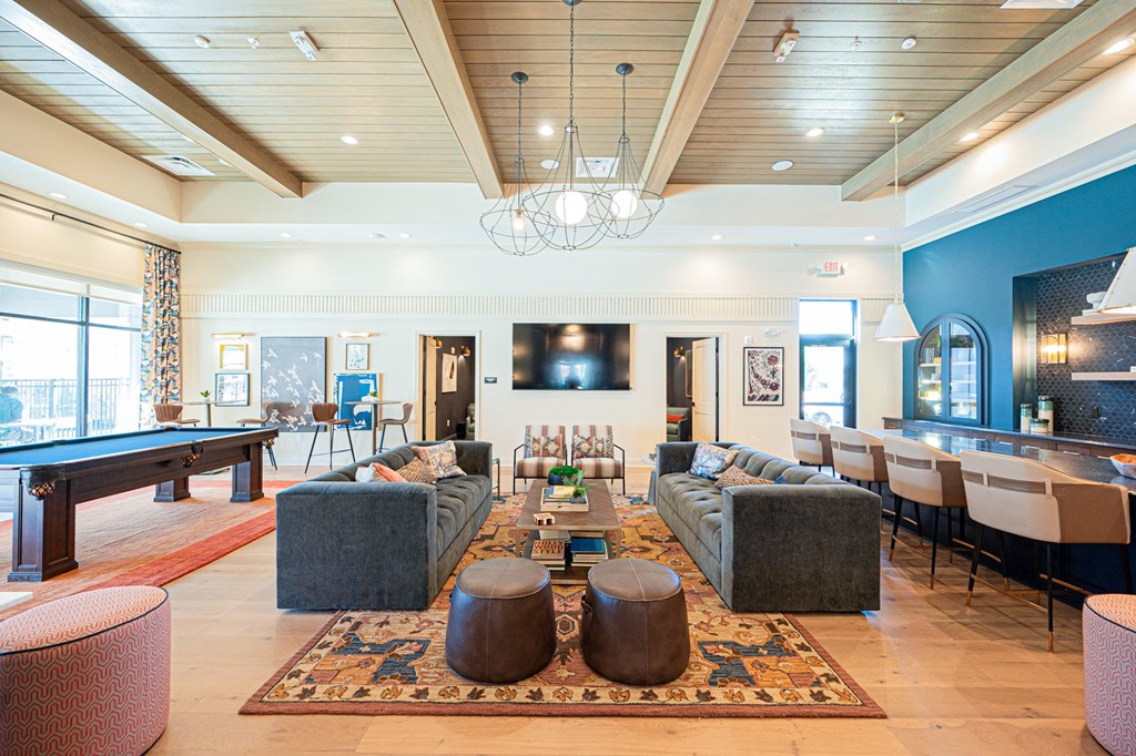 A large, well-lit living room with a pool table and a bar area.