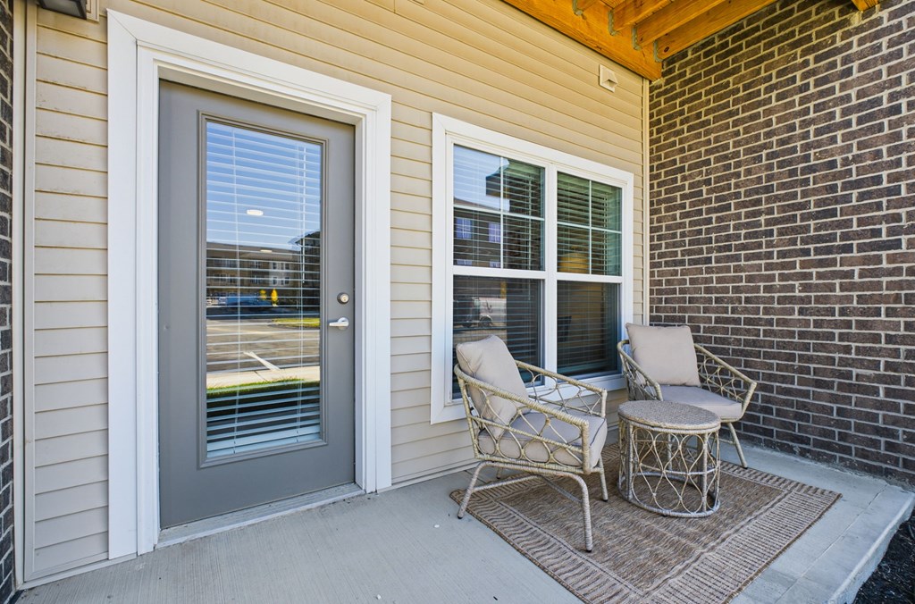 A patio with a chair and table outside a house.