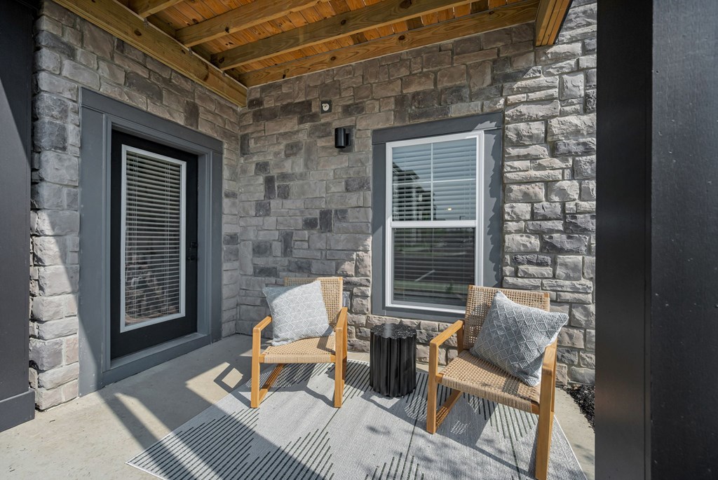 A patio with a wooden bench and a stone wall.