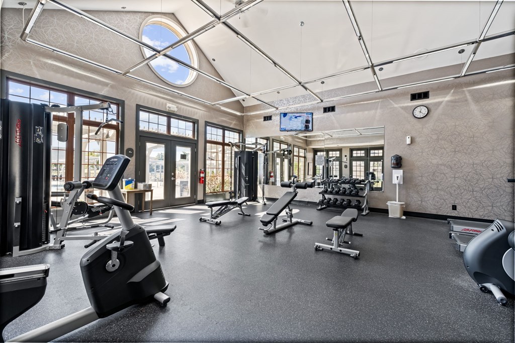 A gym with a variety of equipment including treadmills, weights, and exercise machines.