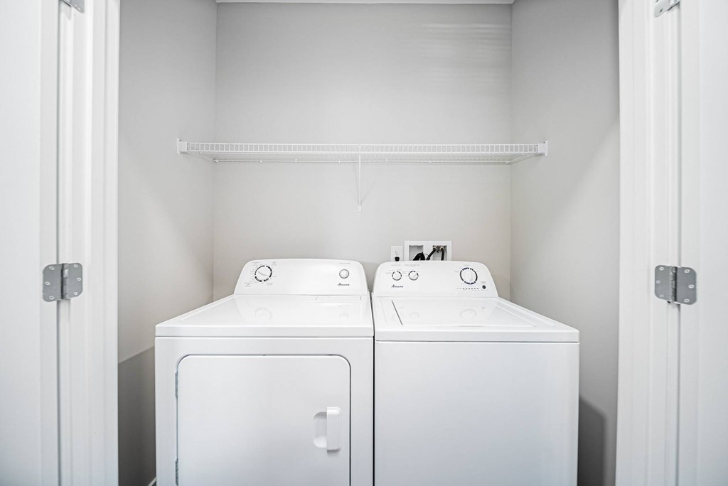 Two white washing machines in a small laundry room.
