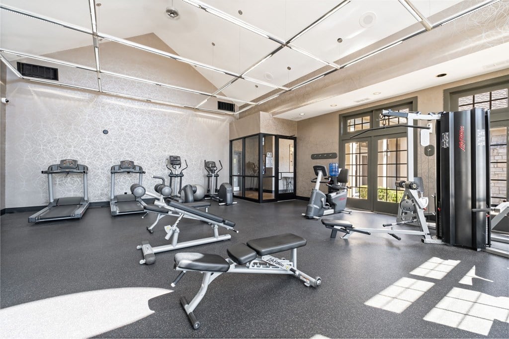 A gym with a variety of equipment including treadmills, weights, and exercise machines.