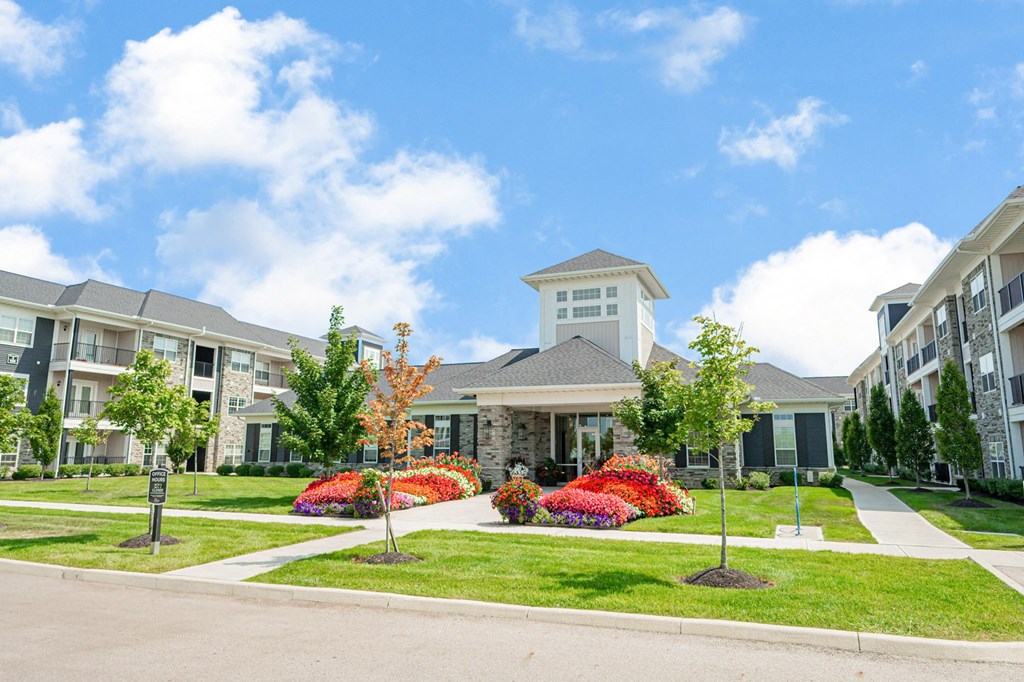 an exterior view of an apartment building with a lawn and flowers
