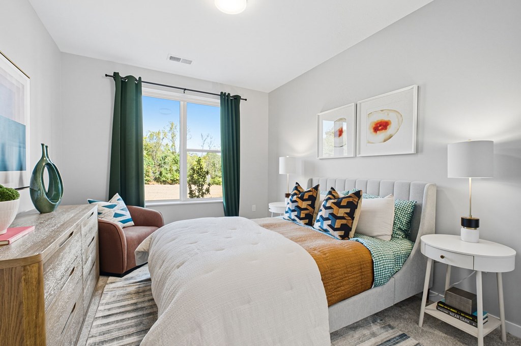 A bedroom with a large bed and a window with green curtains.