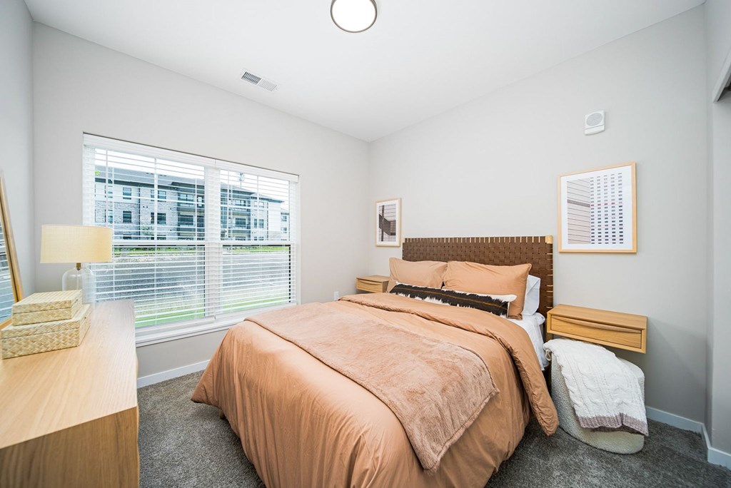 A bedroom with a bed, nightstand, and window.