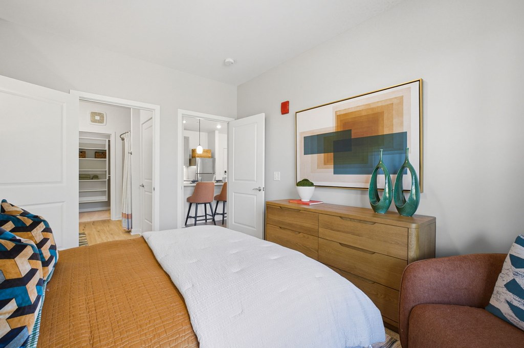 A bedroom with a bed, chair, and painting on the wall.